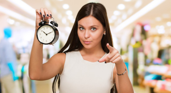 Young Woman Holding Clock And Pointing at a mall