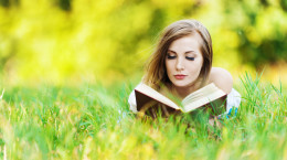 pretty woman lying clearing grass reading book